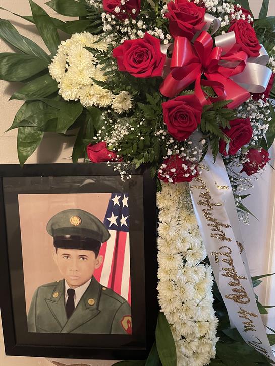 A heartfelt tribute featuring a framed portrait of a young soldier surrounded by vibrant flowers.