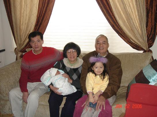 A warm family moment with grandparents, parents, and children on a sofa at home.