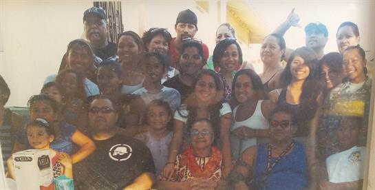 A large family smiles together at a summer barbecue, enjoying each other's company.