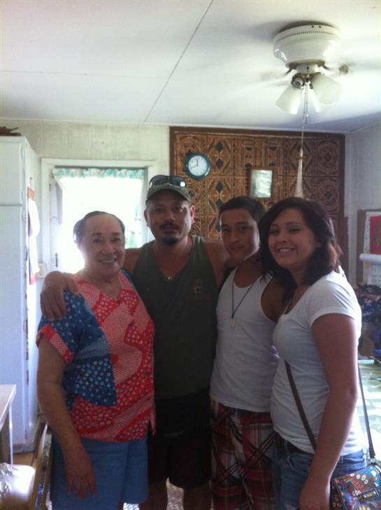 Four family members pose together happily in a rustic kitchen, enjoying each other's company.