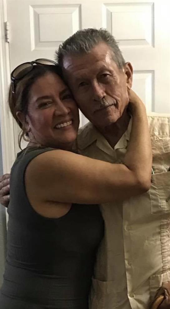 Two family members share a heartwarming hug, smiling broadly in a cozy indoor setting.