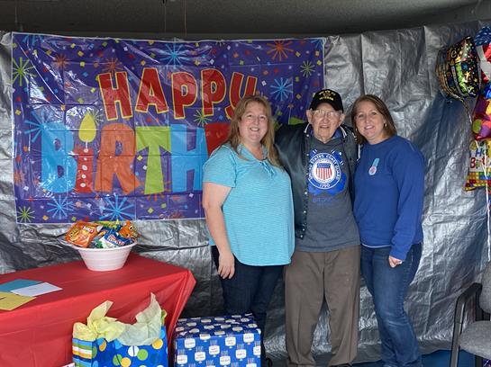 Family gathers to celebrate a birthday in a festive, decorated indoor space.