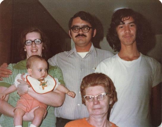 Three generations of a family gather joyfully, sharing smiles and love in a cozy living room.