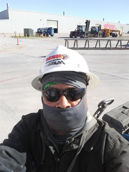A worker in safety gear takes a self-portrait while on a construction job during the day.