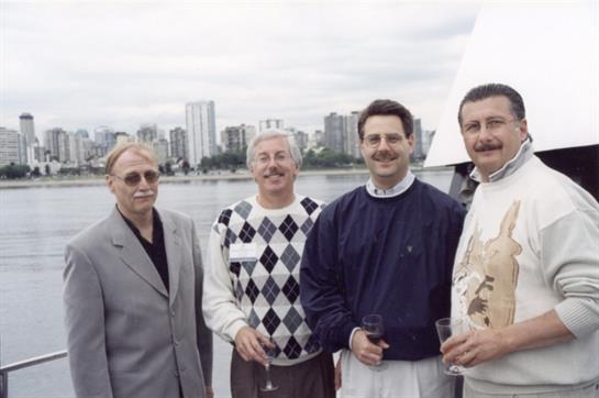 Five men gather on a yacht, holding drinks and enjoying the view of the city skyline.
