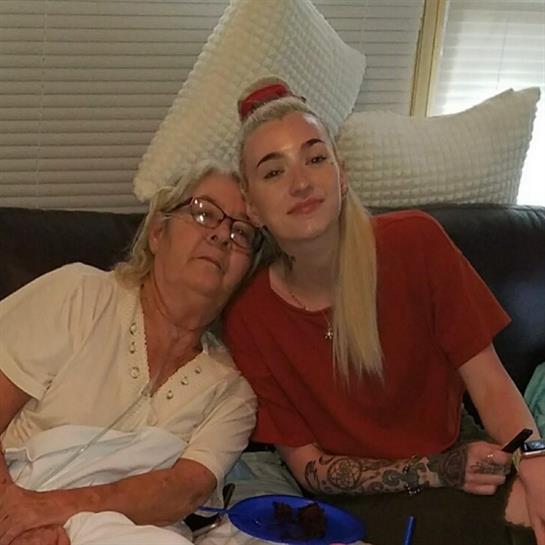 Two women enjoy each other's company on a couch, smiling and relaxing together at home.