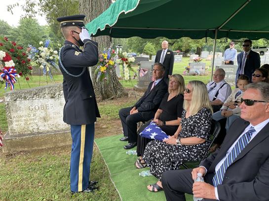 A solemn gathering at a cemetery commemorates a veteran, with family members paying their respects.