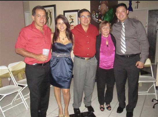 Five family members stand together, smiling and dressed up for a celebration in a cozy setting.