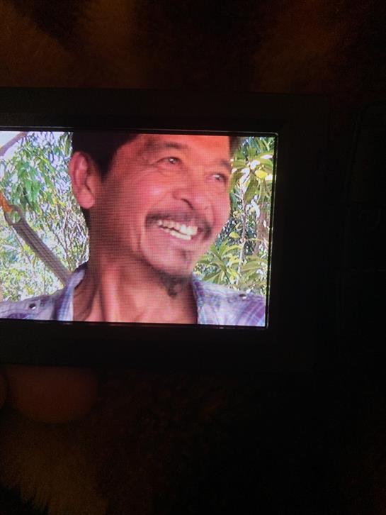 A man joyfully enjoys a vibrant green outdoor space filled with trees and sunlight.
