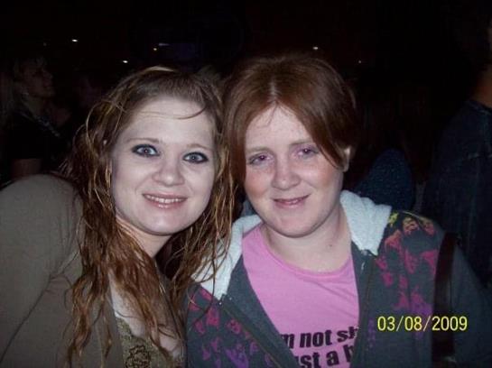 Two friends smiling together, showing their camaraderie at a social event during the night.