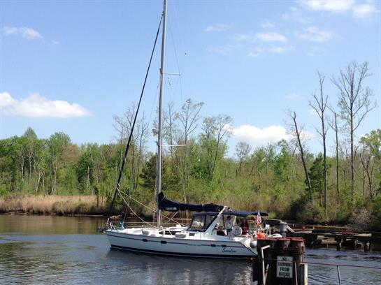 A sailboat rests peacefully at the dock, surrounded by lush greenery under a clear blue sky.