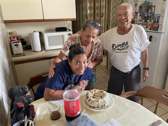 Friends gather around a homemade cake, sharing smiles and laughter in a warm kitchen setting.