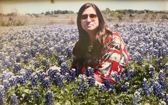 A woman relaxes among vibrant bluebonnet flowers in a Texas field on a sunny spring day.