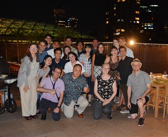 Friends enjoy a lively evening together, posing in front of a city skyline under night lights.