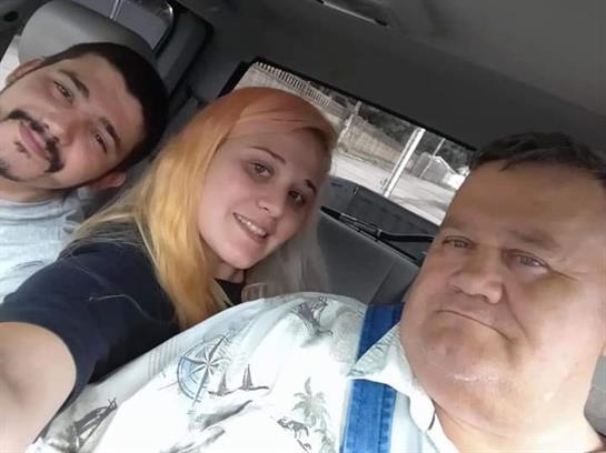 Three people take a selfie inside a vehicle with smiles on their faces while enjoying time together.