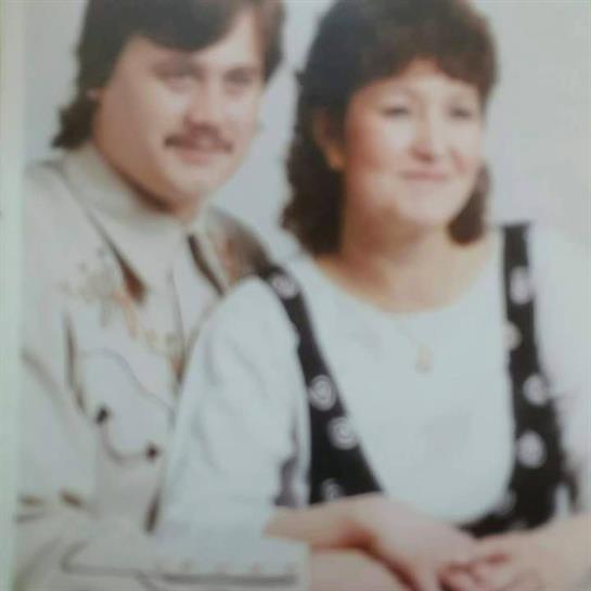 A man and a woman are sitting closely together, smiling at the camera.