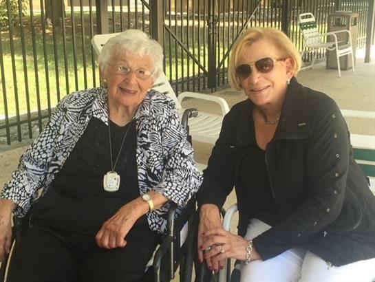 Two women sit together, smiling and enjoying each other's company in a warm, inviting atmosphere.