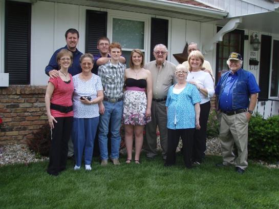 Family members pose in front of a house during a summer gathering, showcasing togetherness and joy.