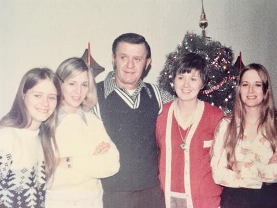 A family celebrates together around a decorated Christmas tree, sharing joyful moments.