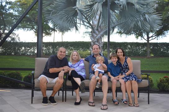Family enjoys a sunny day at a tropical resort, gathering on a comfortable bench.