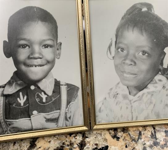 Two framed black and white portraits display a boy and girl smiling, capturing their youthful joy.
