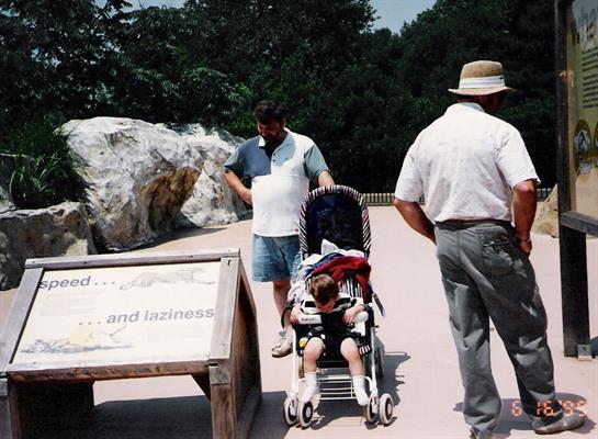 Family enjoys a day at the park with a stroller while engaging with a sign about relaxation.