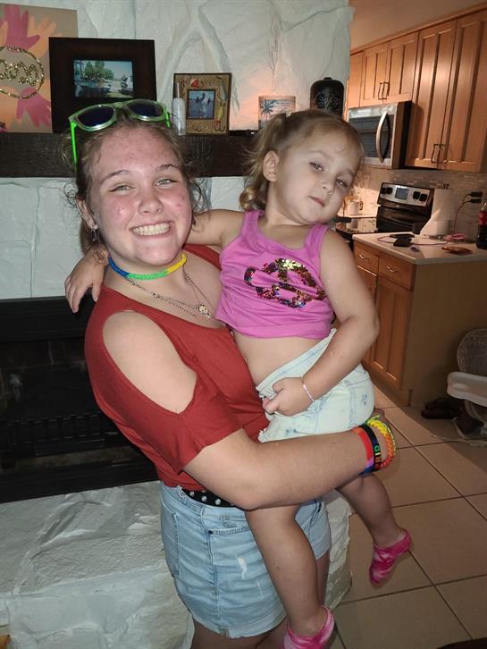 A young woman joyfully embraces a little girl in a vibrant kitchen setting during family time.