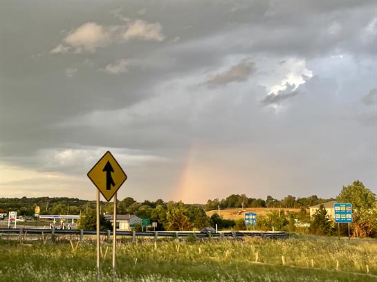 Dark clouds loom over the highway as rain begins, warning of traffic changes ahead.
