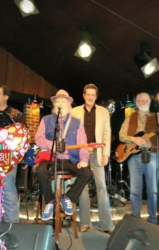 Four musicians entertain an audience with live music and celebration decorations in the evening.