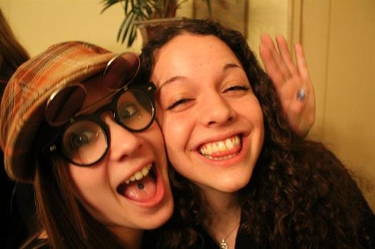 Two friends share big smiles and laughter while enjoying a fun moment during a party.