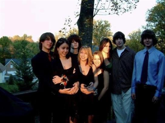 Friends pose together in elegant outfits, enjoying a warm evening in a picturesque park.