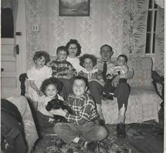 Adults and children gather in a vintage living room, sharing laughter and joy together.
