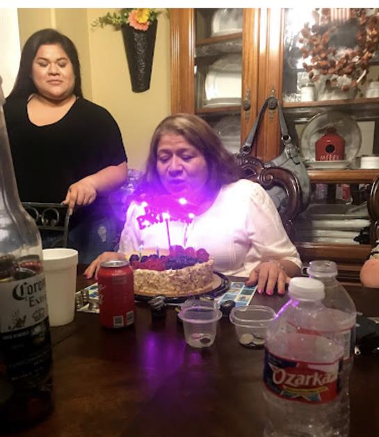 Family and friends gather to celebrate a birthday with a cake and joyful atmosphere in the evening.