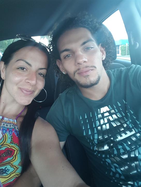 Happy couple sitting in a parked car, posing together with bright smiles on a sunny day.