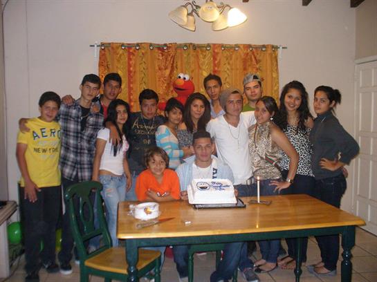 Friends and family gather to celebrate a birthday with joyous expressions and a decorated cake.