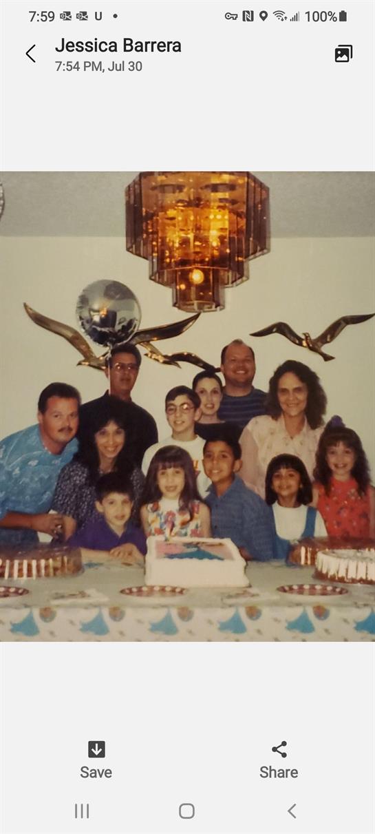 A happy family poses for a photo around a decorated cake at a celebration.