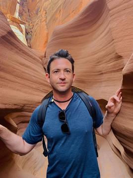 A traveler stands amid the stunning sandstone formations of Antelope Canyon, enjoying the sunlight.