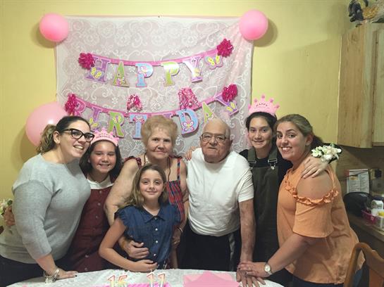 Group of family members gather to celebrate a birthday with decorations and joyful expressions.