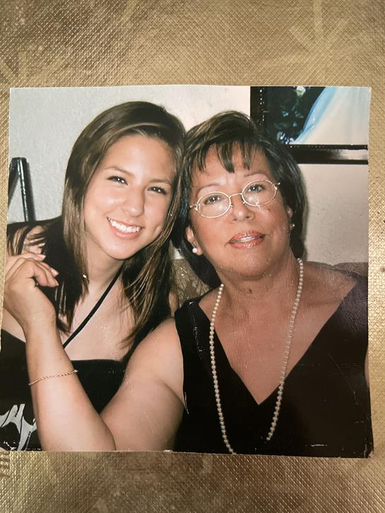 Two women smile warmly while sitting close together, celebrating a special moment in life.