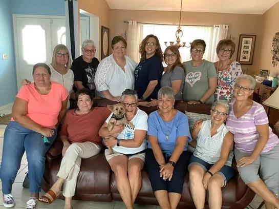 A group of friends poses together with a dog in a warm, inviting living room filled with laughter.