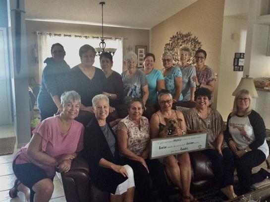 A group of friends poses together in a living room, celebrating a momentous occasion with smiles.