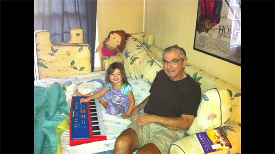 Grandfather and granddaughter share a joyful afternoon, playing music together on a keyboard.