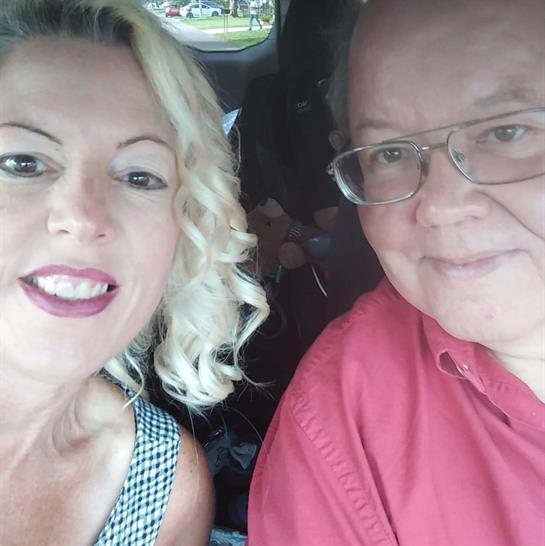 Smiling couple shares a joyful moment inside a parked car during a bright afternoon.