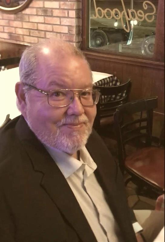 An older man with glasses and a white beard enjoys a meal at a cozy restaurant.