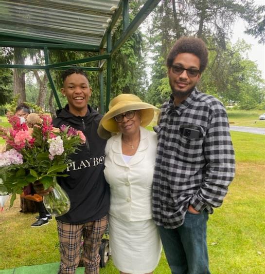 Family gathers in a sunny park, holding flowers and enjoying time together.