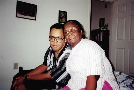 Two family members sit closely in a cozy living room, smiling and enjoying each other's company.