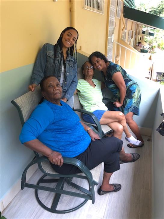 Four friends share laughter and smiles while relaxing on a balcony during a warm summer afternoon.