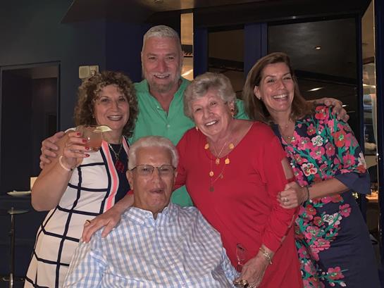 Friends gather joyfully at a vibrant event, enjoying drinks and sharing laughter in the evening.