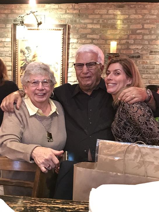 Three people, two women and one man, share laughter and embrace in a welcoming atmosphere.