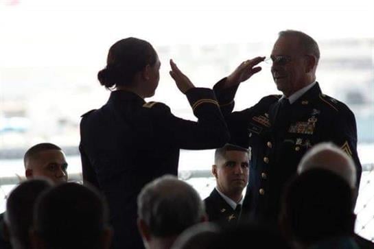 A military officer receives a formal salute during a promotion ceremony at sunset.